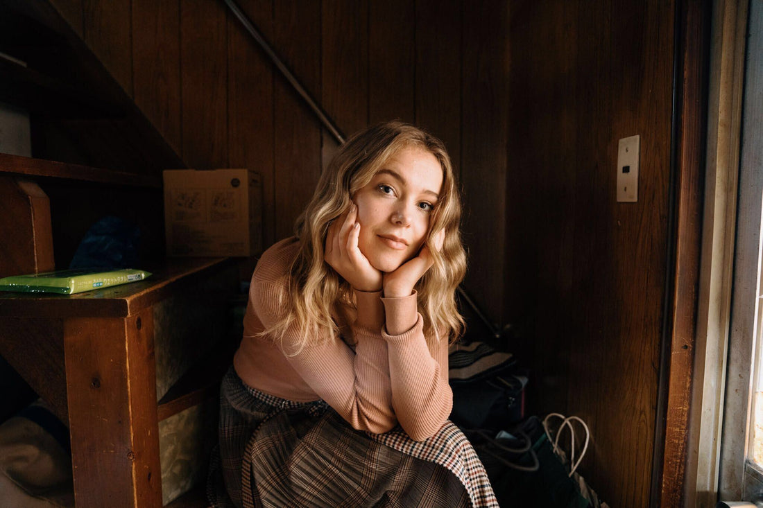 blond-young-woman-sitting-down-with-wood-background.jpg