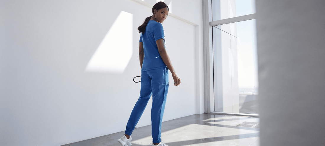 nurse-wearing-blue-jaanuu-scrubs-white-room.png