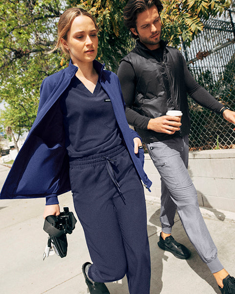 A woman and a man wearing jackets walking.