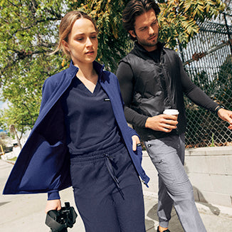 A woman and a man wearing jackets walking.